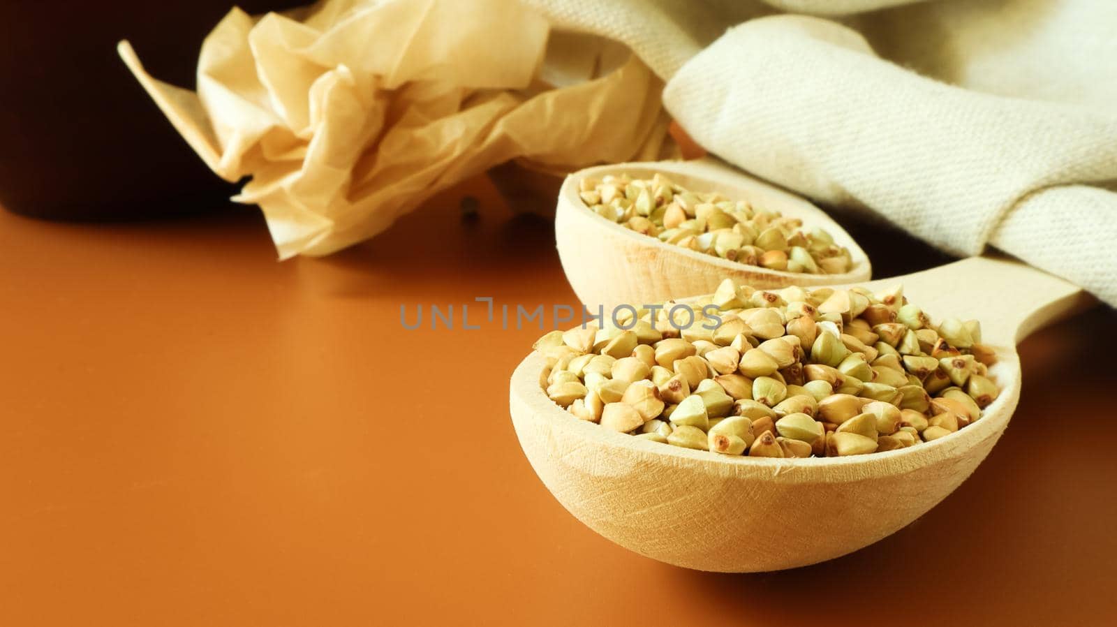 Green buckwheat in a wooden spoon on a brown background. Great food. healthy groats. Organic raw non-fried vegetarian food. The concept of a healthy and balanced diet. Dietary foods. Copy space.