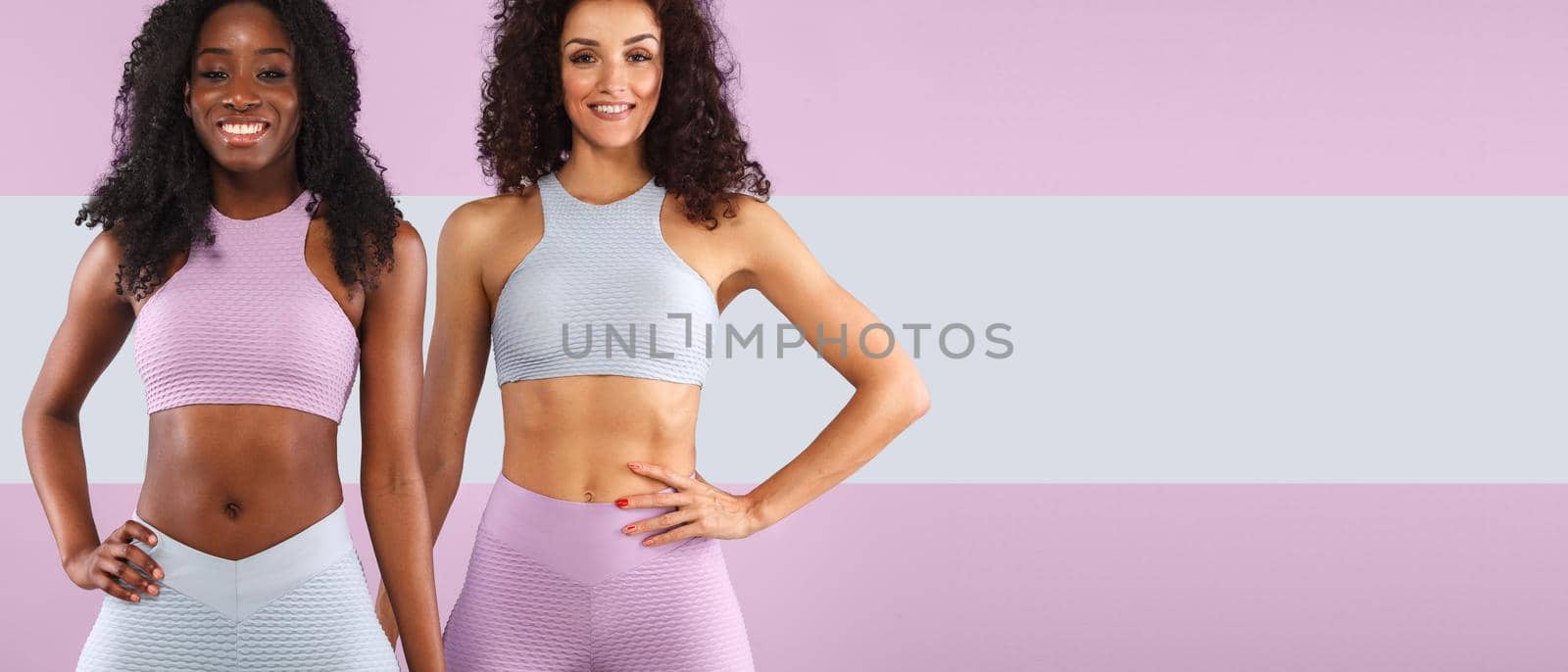 Attractive excited fitness girls in sportwear jumping of joy isolated over light background