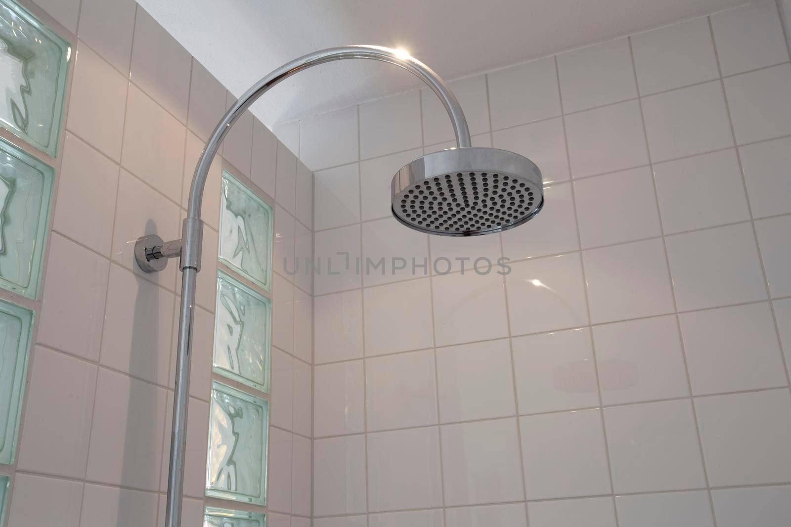 close up on head, rain shower in modern bathroom with white tiles stylish new design clean