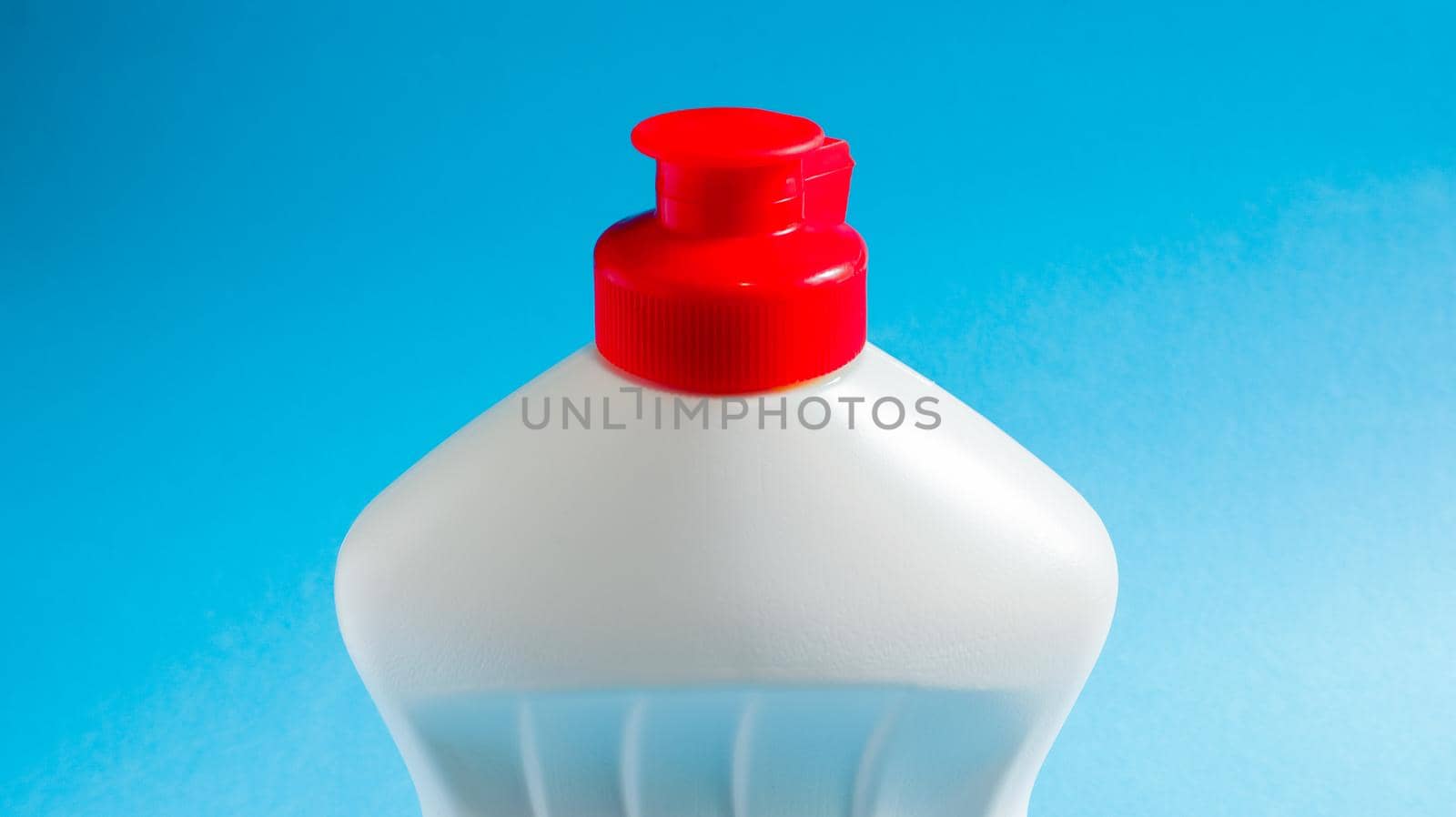 White plastic bottle with dishwashing detergent, bleach or fabric softener on a blue background. liquid washing powder. The concept of cleaning