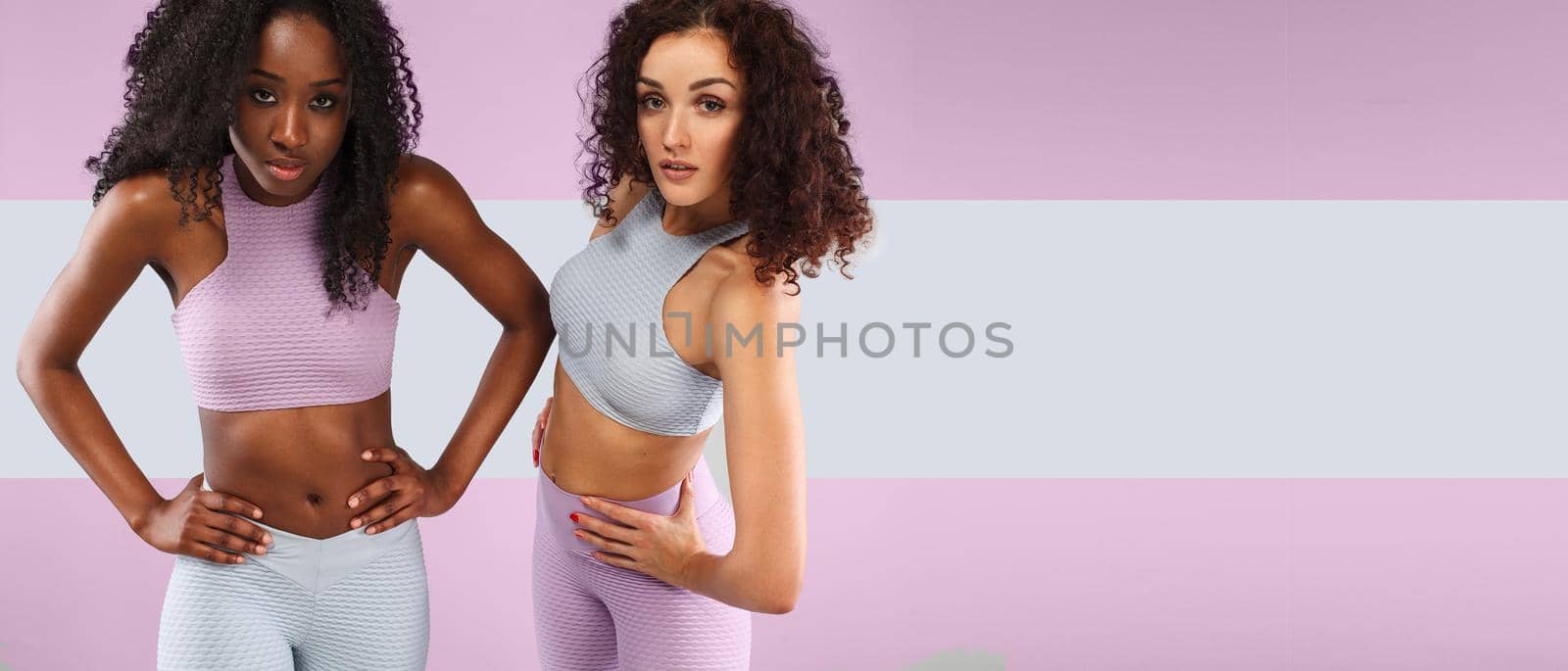 Two fitness women in sportswear isolated over gray background. Sport and fashion concept wit chopy space. by MikeOrlov