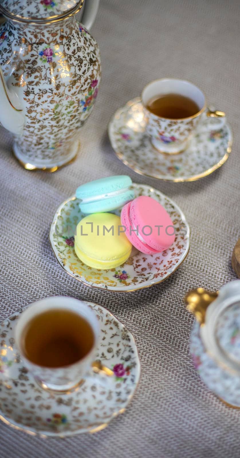 Traditional table with cup of tea and tea pot and colorful macaron lovely cozy table at home,Mother's Day tea setting with teapot, close up