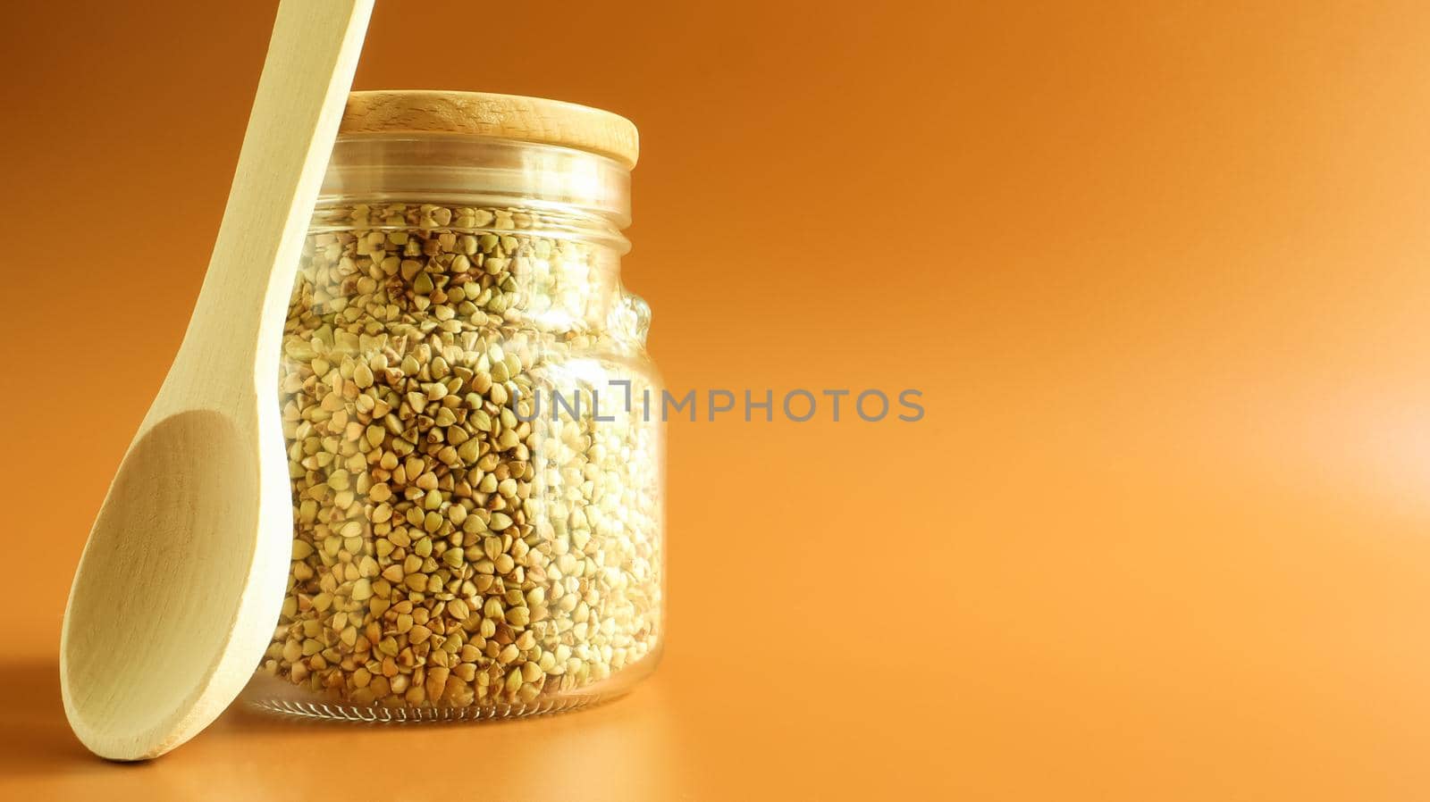 Green sprouts of raw organic buckwheat in a glass cereal jar with a wooden spoon. Vegan food concept. Organic food. The concept of diet, weight loss, healthy and proper nutrition. Copy space for text