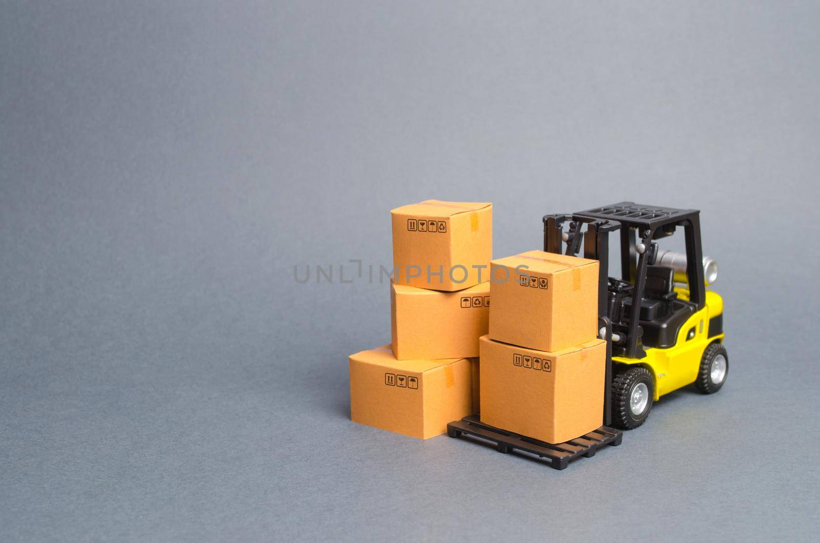 Yellow Forklift truck with cardboard boxes. Service storage of goods in a warehouse, delivery and transportation. Freight shipping, delivery. Import and export, commodity exchange with other countries