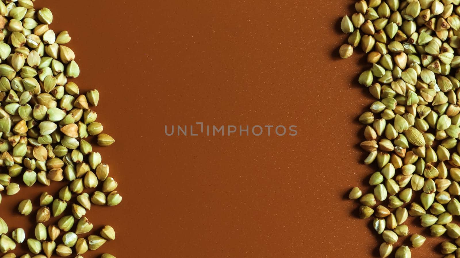 Background from raw organic green buckwheat porridge, vegan food. Texture of scattered buckwheat groats. Seeds are triangular in shape. Organic food. The concept of diet, weight loss, healthy eating
