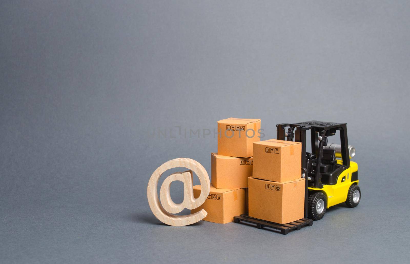 Yellow Forklift truck and cardboard boxes and email symbol commercial AT. E-commerce. sales of goods through online trading platforms. shopping online. development of Internet network trade.