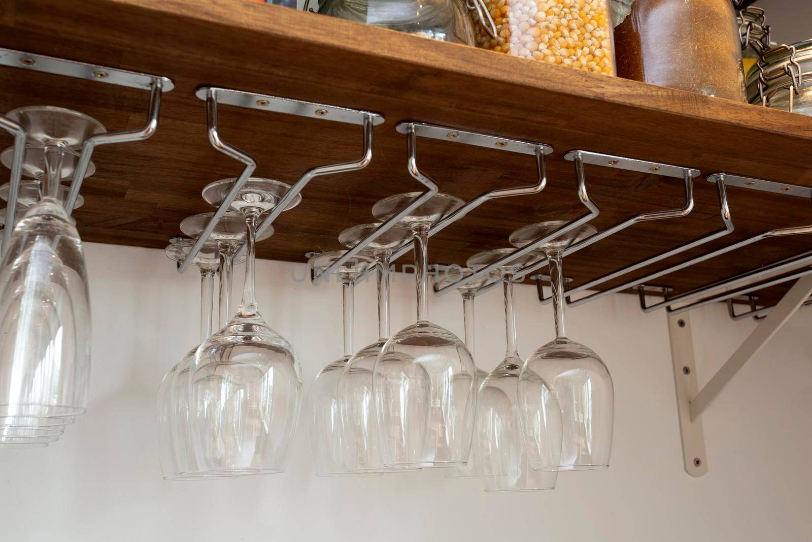 Wine glasses hanging in holder. organized inside cupboard. home interior storage close up