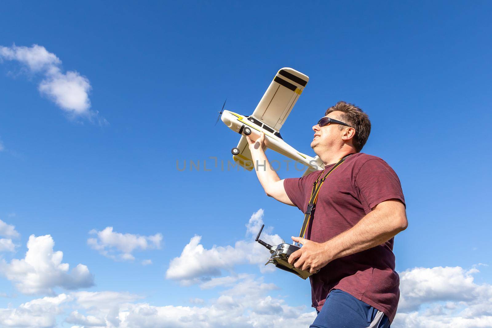 Middle-aged man launching a model of the radio remote controlled airplane outdoor on a background of the sky