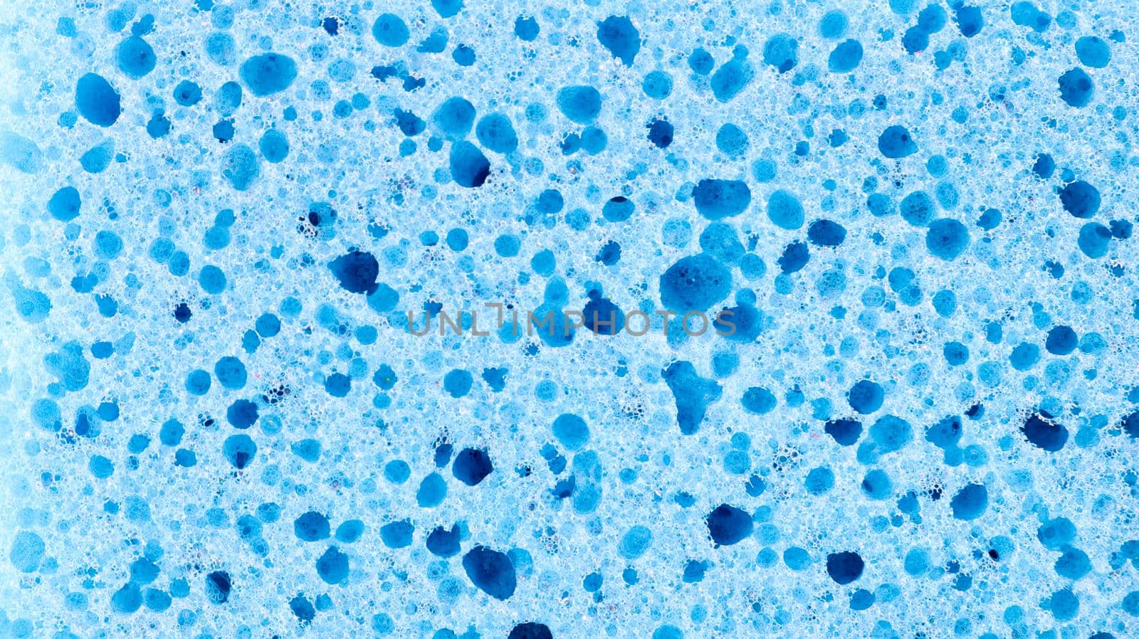 Background in the form of a porous structure in blue. Macro sponge. Close up blue sponge surface for textured background. copy space