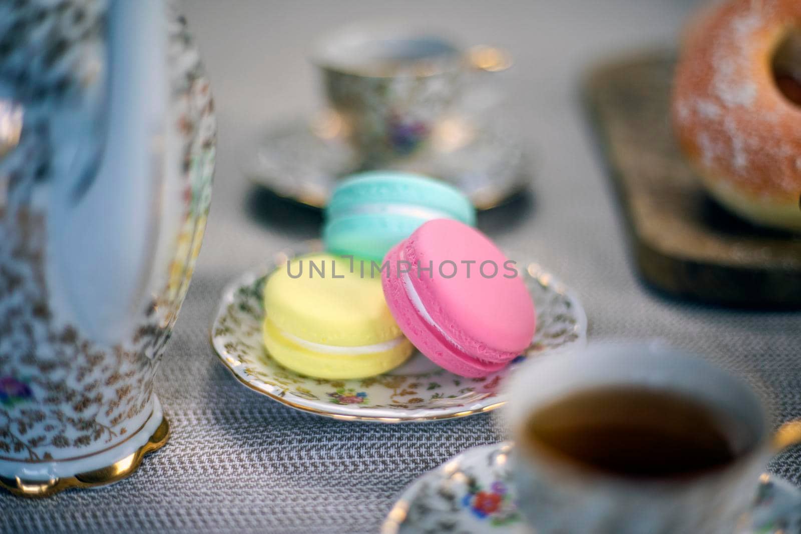 Traditional table with cup of tea and tea pot and colorful macaron lovely cozy table at home,Mother's Day tea setting with teapot, close up