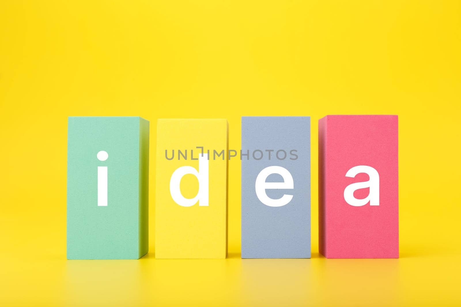 Concept of idea, creativity, start up or brainstorming. Single word idea written on multicolored rectangles in a row on bright yellow background