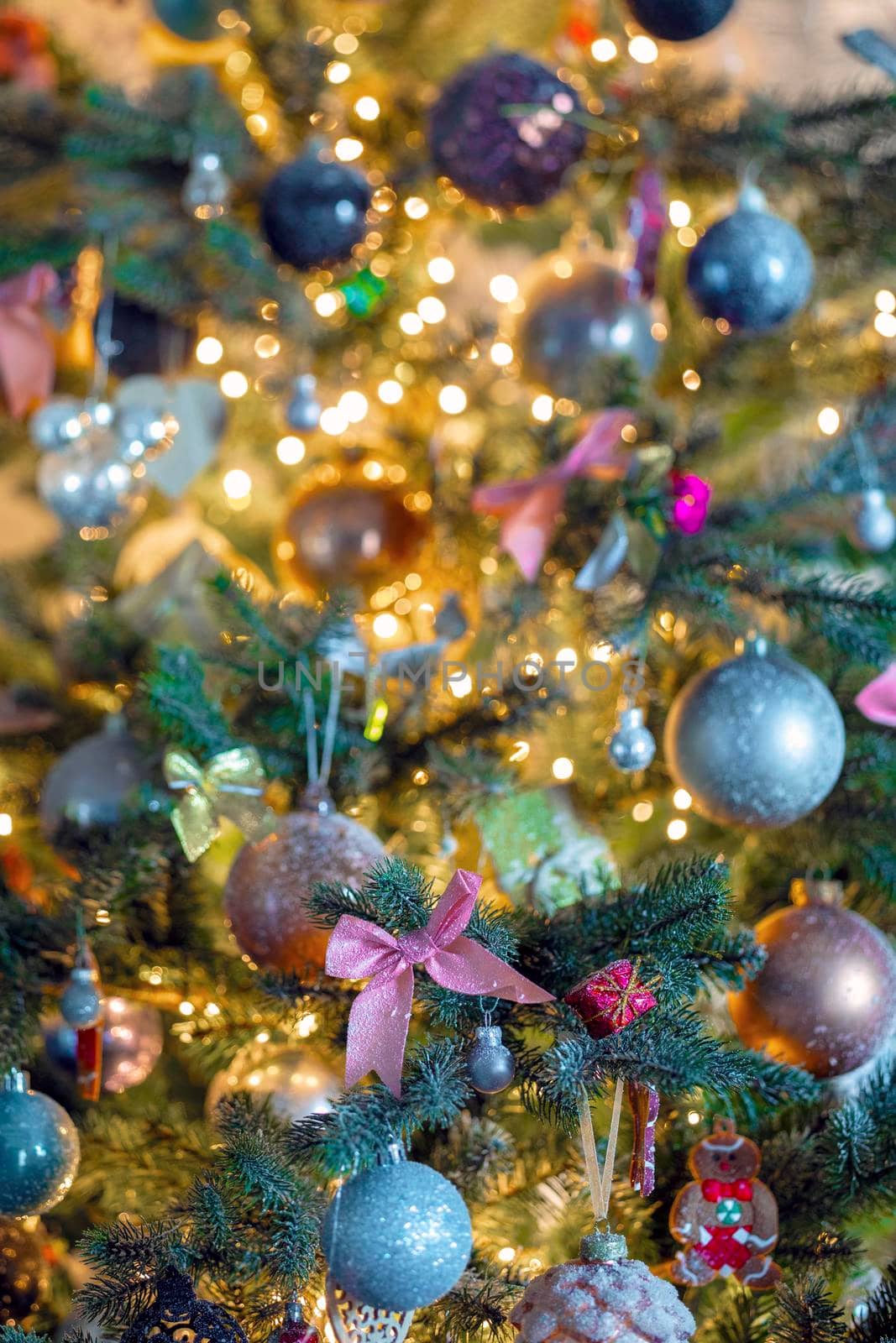 Decorated Christmas tree close-up with sparkling baubles and bokeh christmas lights, pink bow and glitter balls, copy space space for text