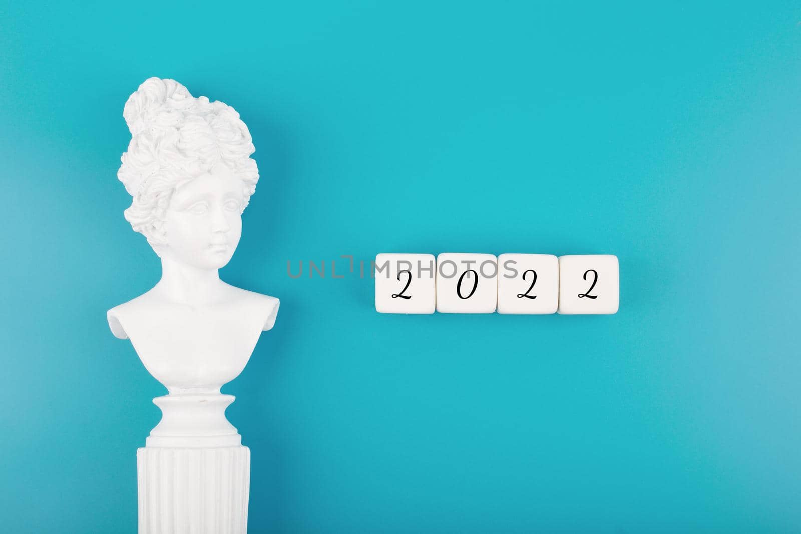 Creative trendy 2022 concept. Numbers written on white cubes next to white gypsum woman figure on blue background by Senorina_Irina