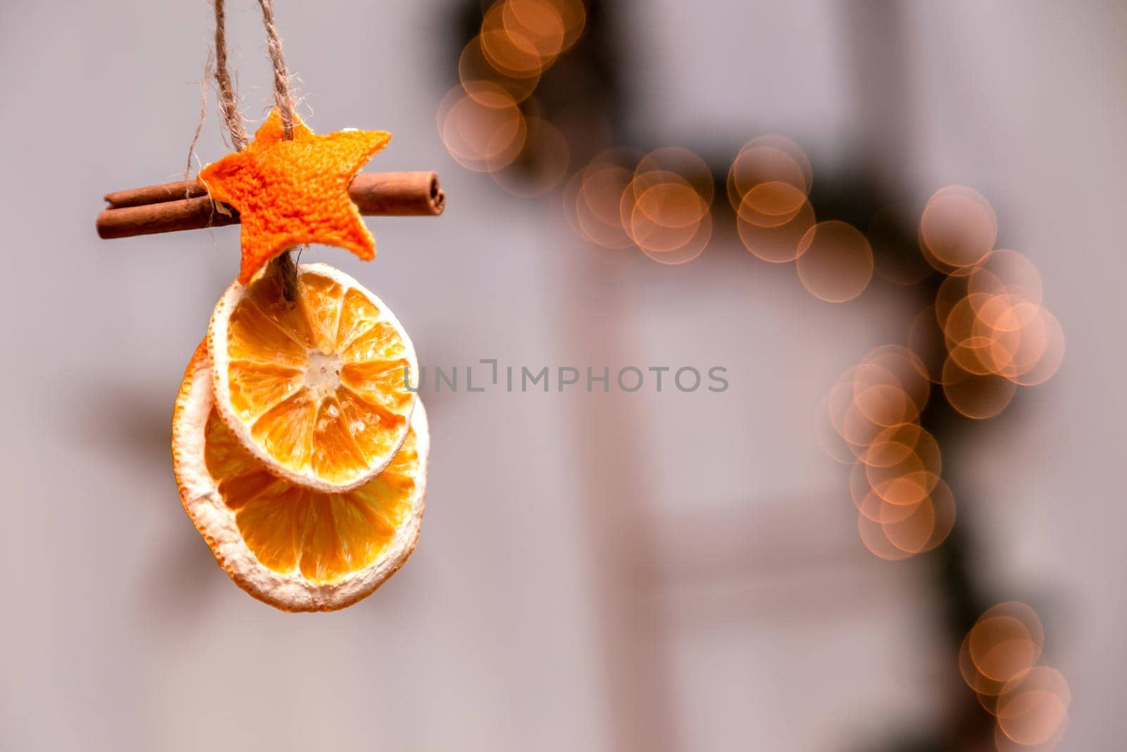 Hanging Christmas decoration of dried oranges, tangerine and cinnamon stars with copy space for text. holiday concept. blurred background by lunarts