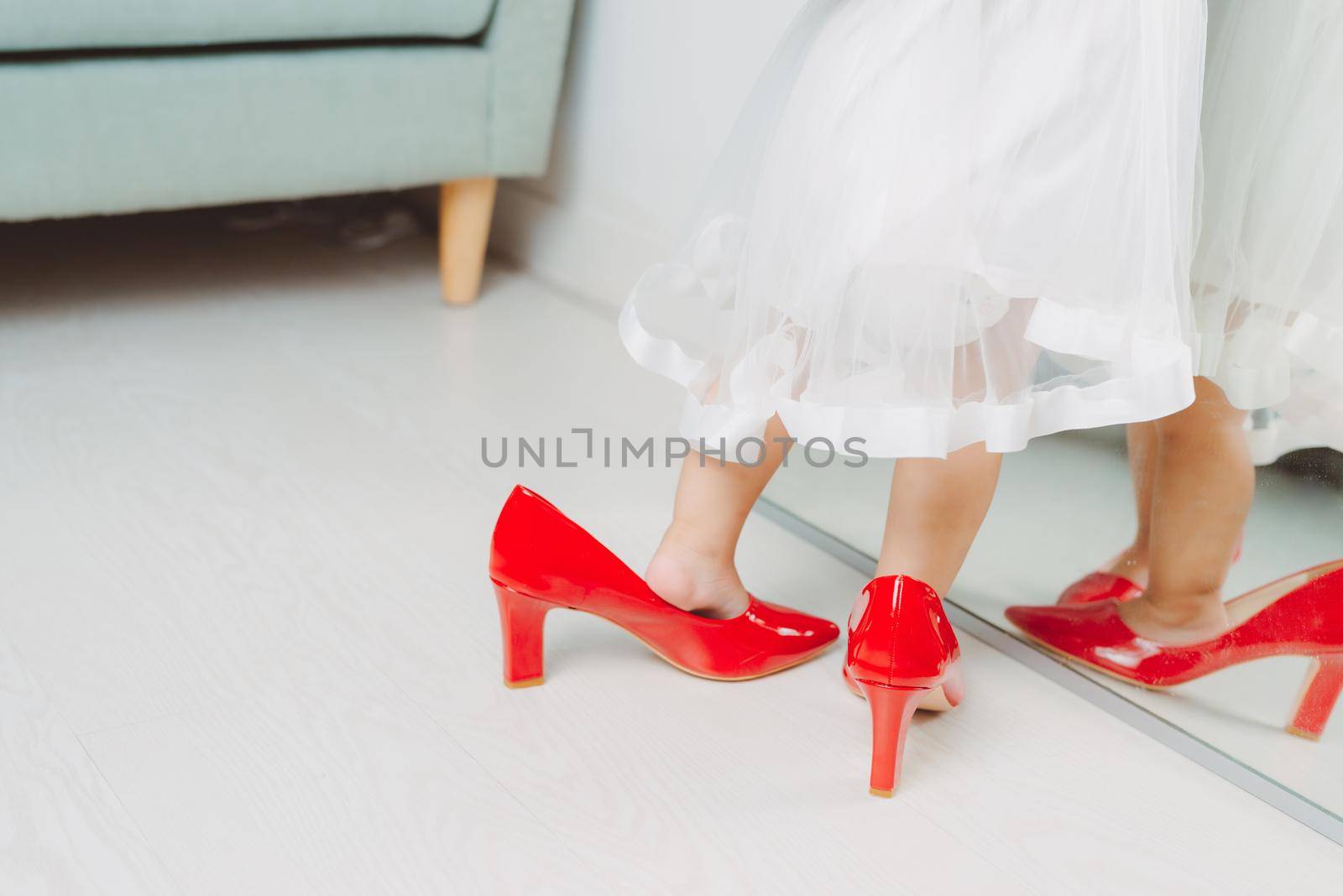 Legs of little girl wearing red high heels