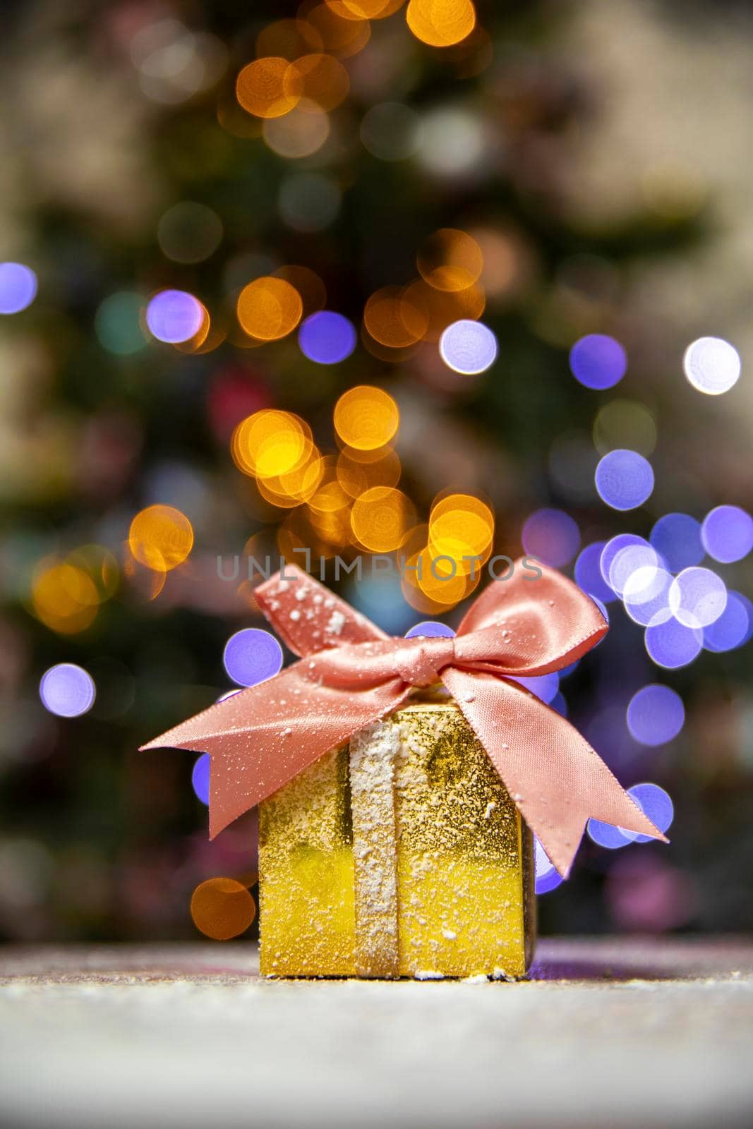 Gold Christmas gifts with pink bow, with Christmas tree bokeh lights background and copy space, Holiday, present xmas concept space for text