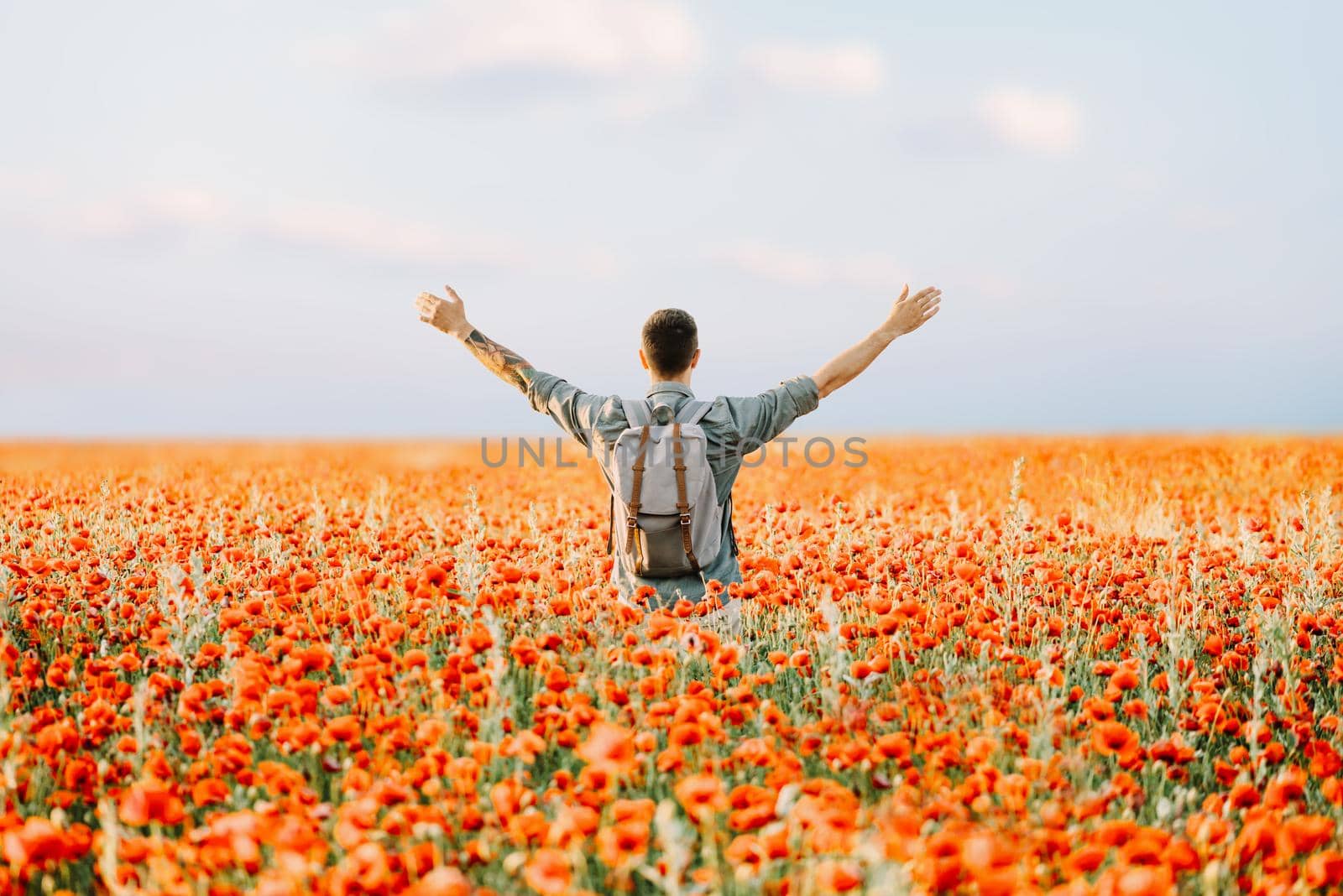 Happy traveler man standing in poppies flowers meadow. by alexAleksei