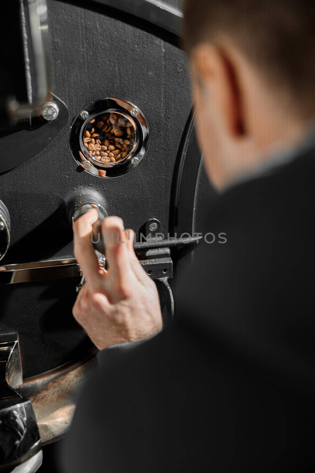 Young specialist worker is roasting coffee in hangar