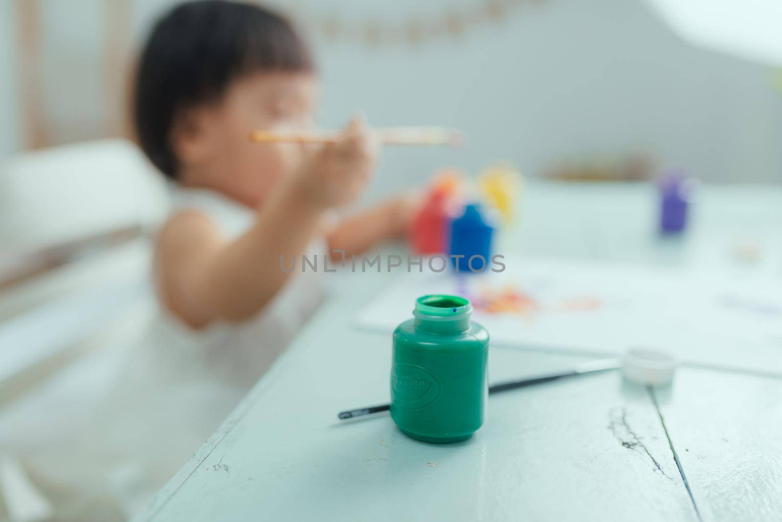 Cute adorable baby girl learning painting with water colors