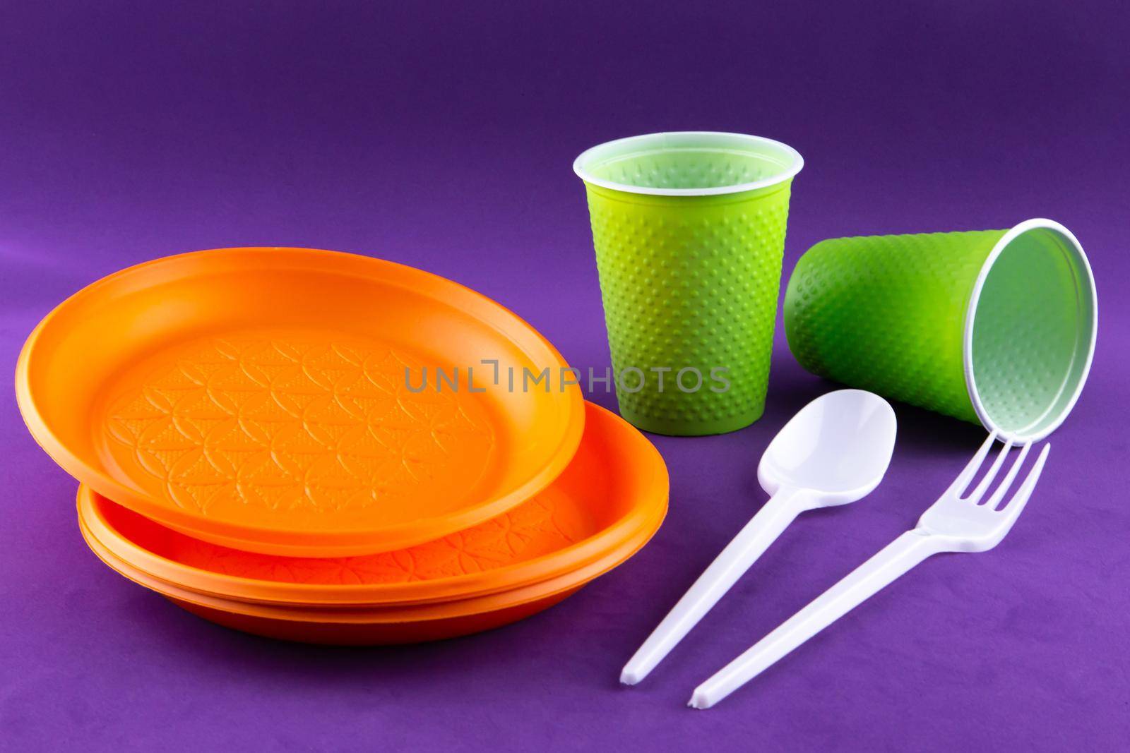 Plastic orange green waste collection on purple background. Concept of plastic pollution and ecology problem