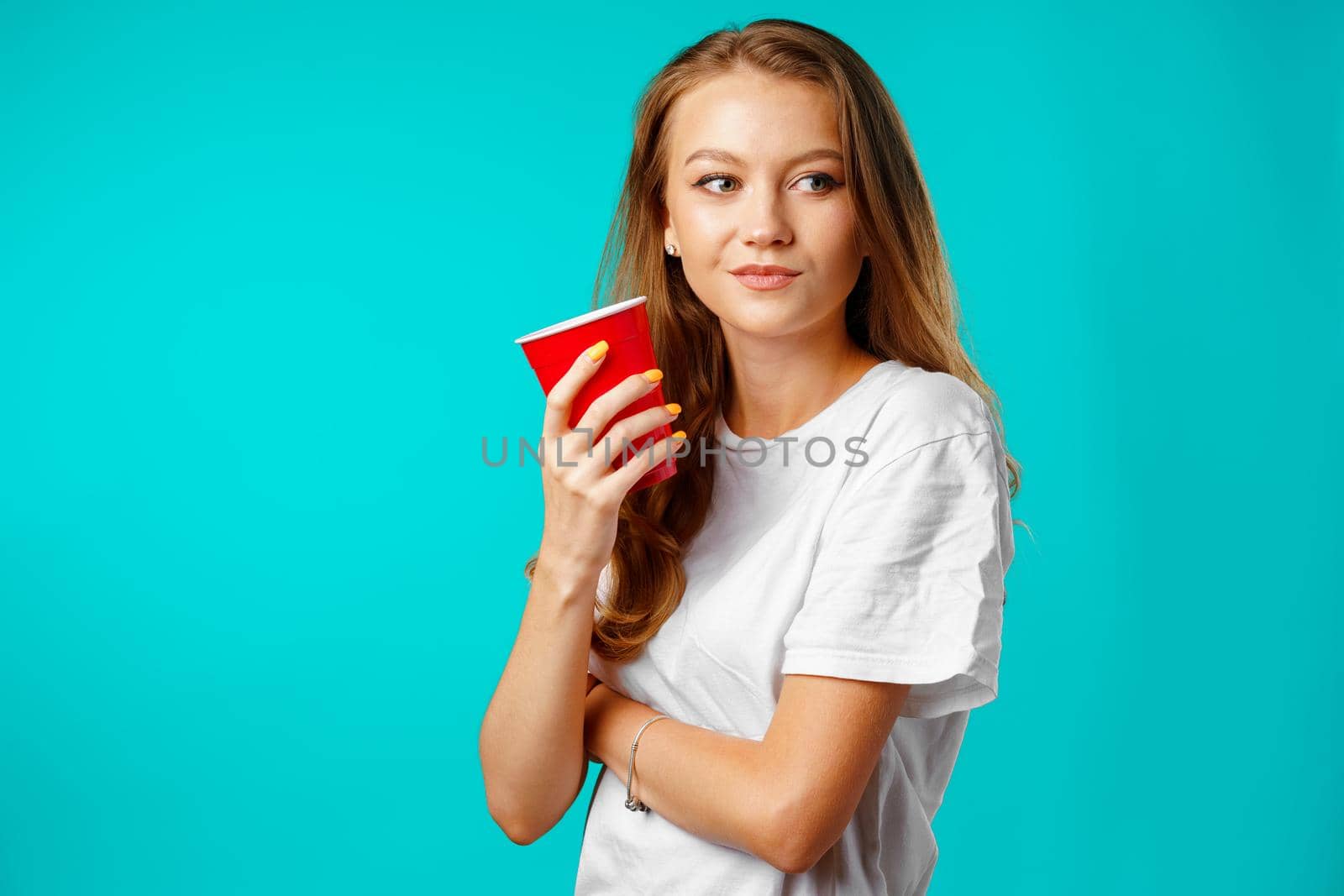 Young attractive woman holding a cup of hot drink against blue background