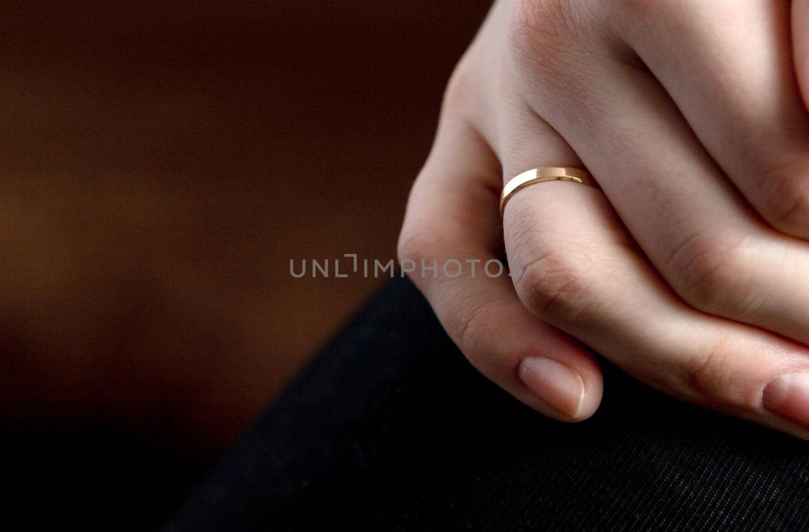 Closeup shot of a person s hand with a wedding ring on a brown surface. by lunarts