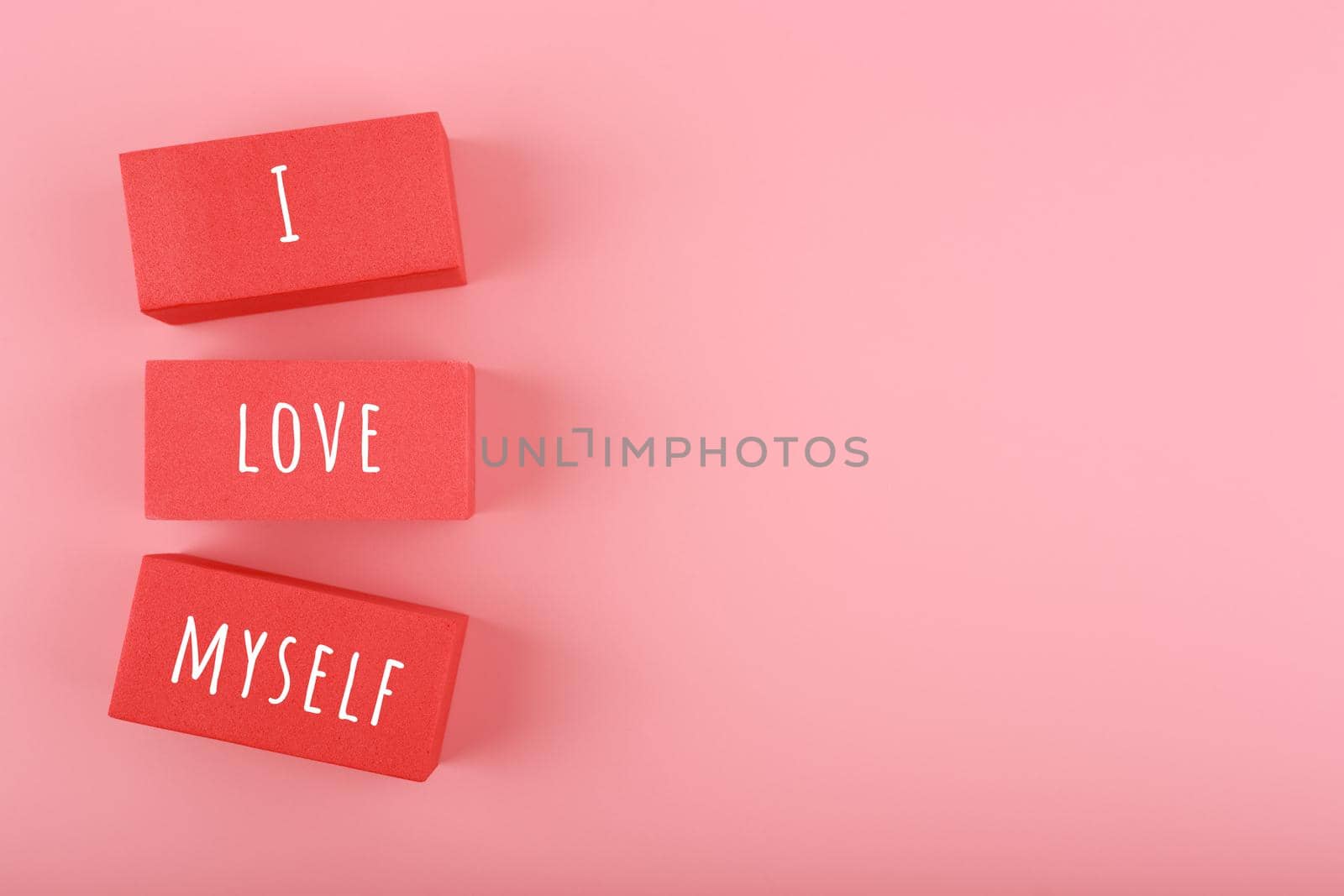 Minimal trendy concept of mental health and self love and acceptance. I love myself written on red toy rectangles in a row against bright pink background with copy space