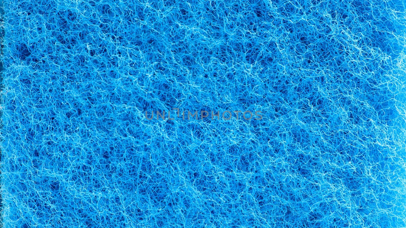 Background in the form of a porous structure in blue. Macro sponge. Close up blue sponge surface for textured background. copy space