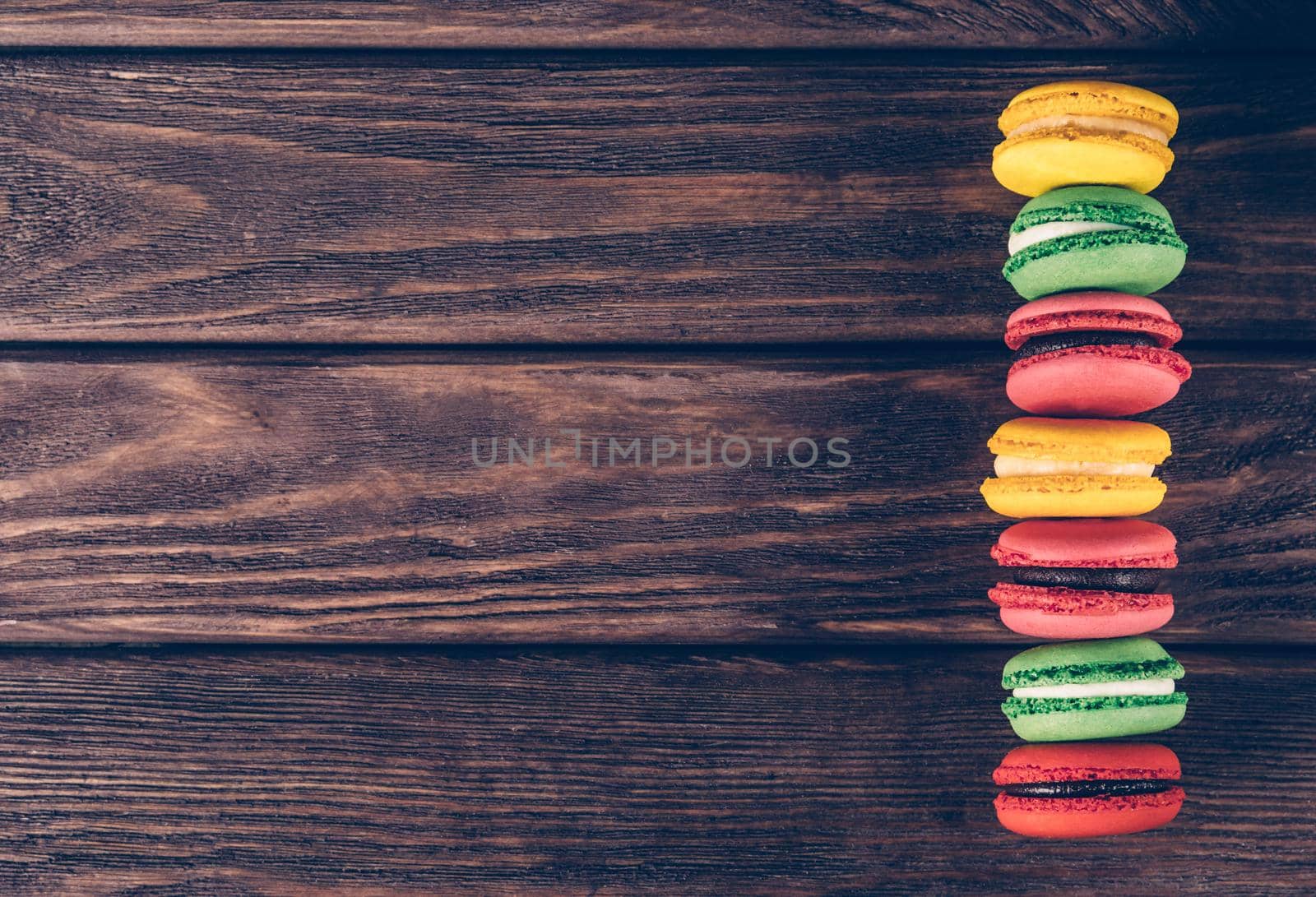 Row of colorful sweet macaroons on wooden background, copy-space in left part of image.