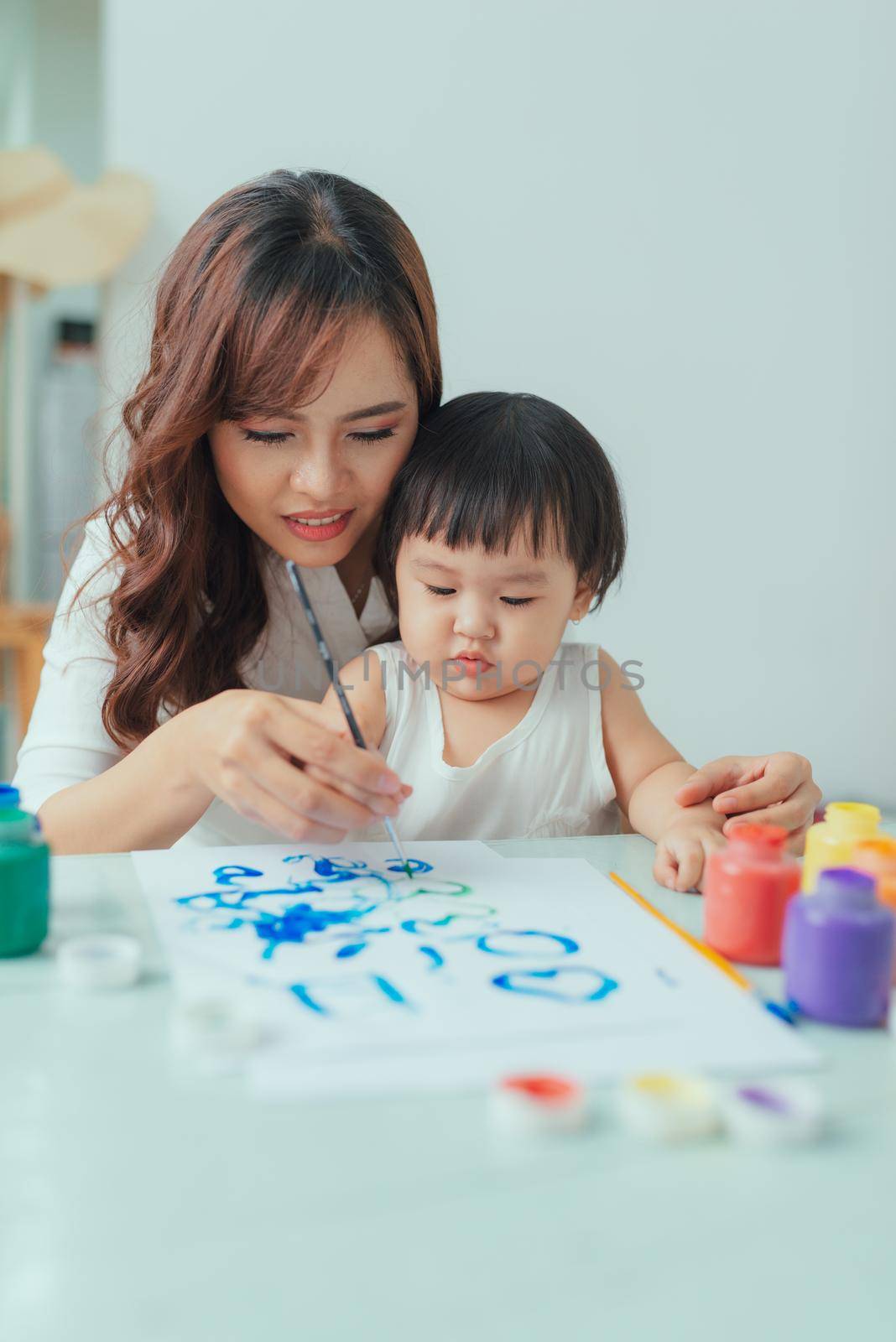 Little girl painting with her mother at home by makidotvn