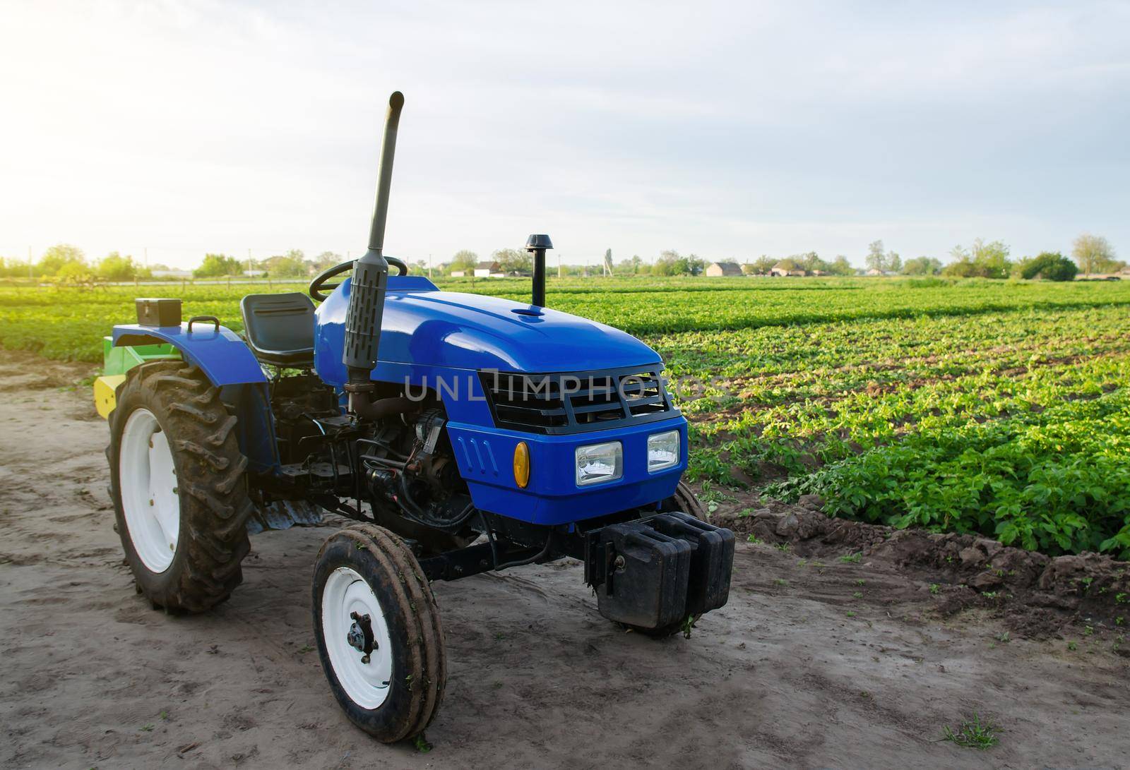 Blue farm tractor stands on field. Application of agricultural machinery in harvesting. Modernization and automation of farm processes. Subsidies and tax refunds for the purchase of new work equipment