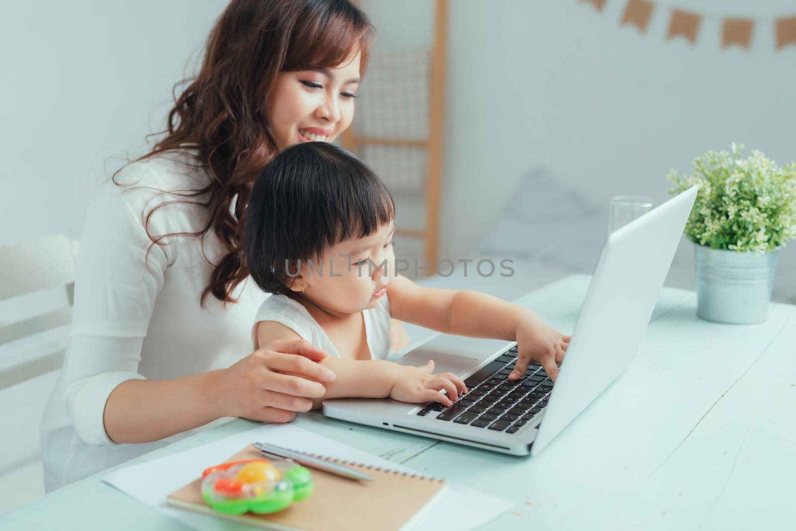 Young mother on maternity leave trying to freelance by the desk with toddler child. by makidotvn