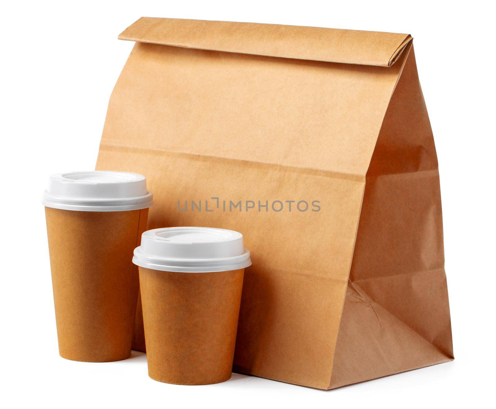 Craft paper bag and coffee to go cups on white background close up