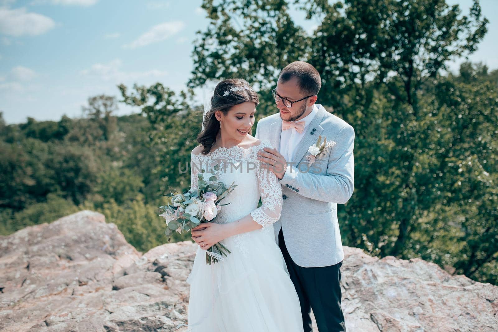 Wedding photo of the bride and groom in a gray-pink color on nature in the forest and rocks. by lunarts