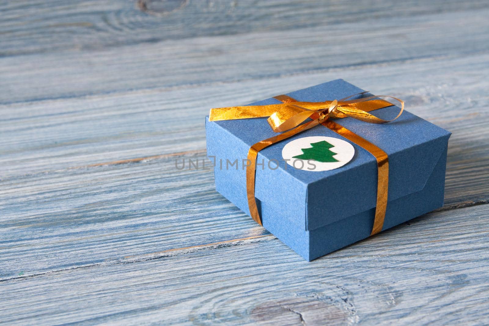 Blue gift box with golden ribbon on a blue wooden background for Christmas and New Year, birthday or Valentine's Day