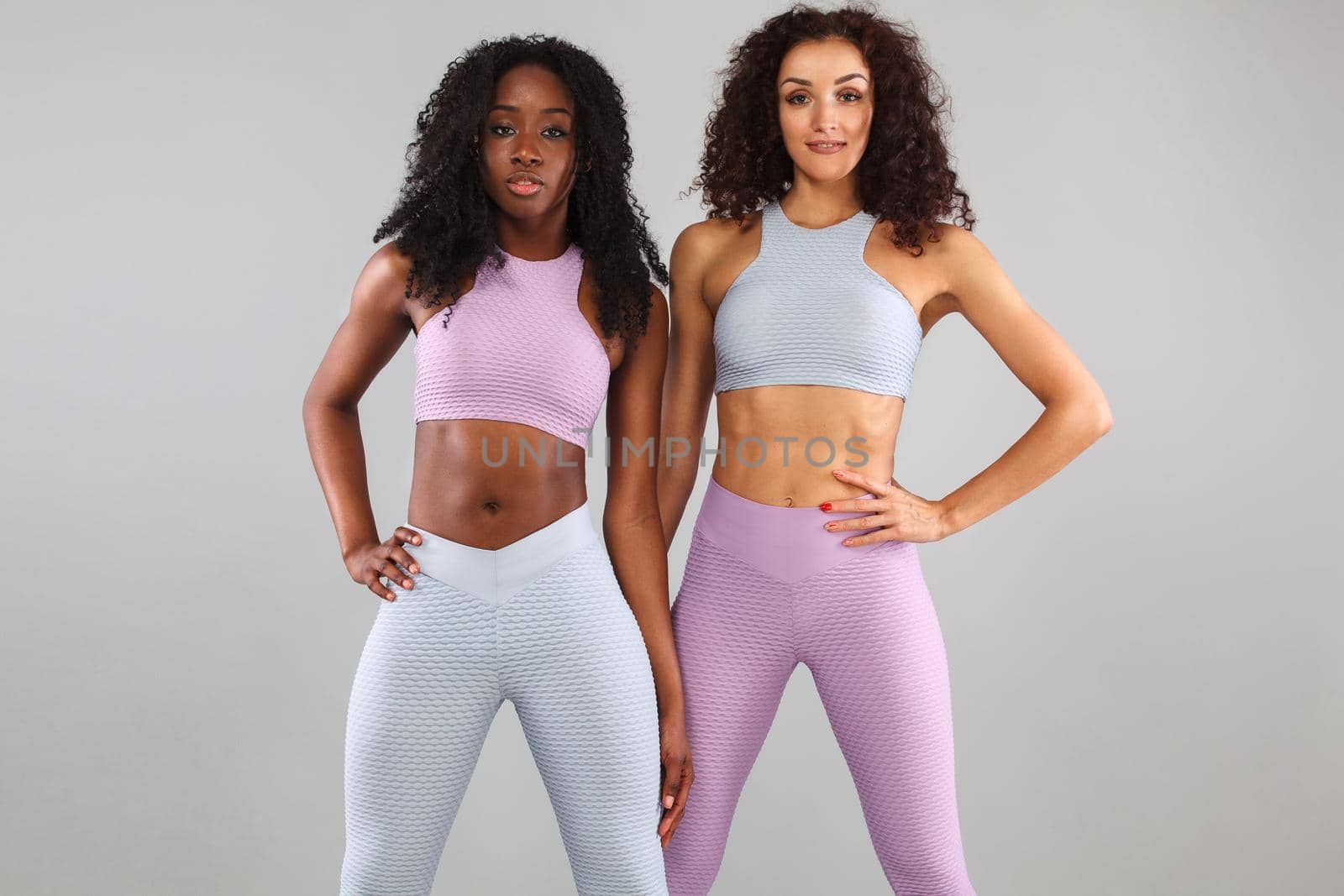 Two fitness women in sportswear isolated over gray background. Sport and fashion concept with copy space. by MikeOrlov