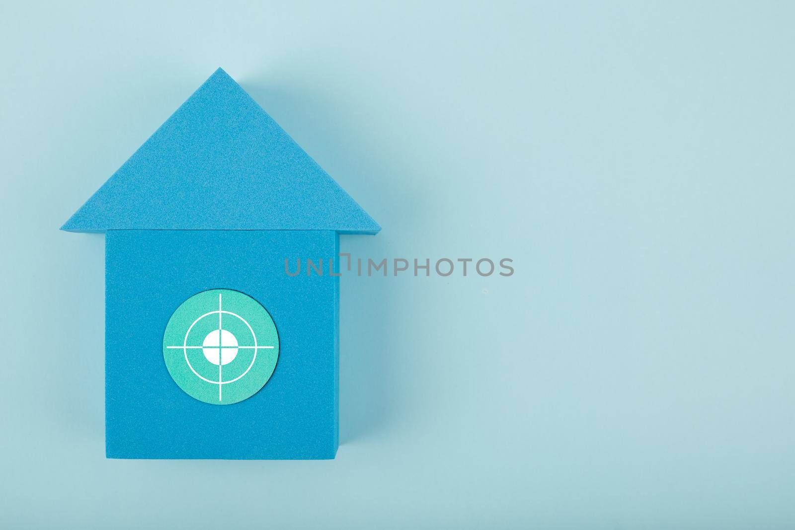 Mortgage, loan or saving money for home and investing in real estate trendy concept. Blue toy house with white target in the middle against bright blue background with copy space