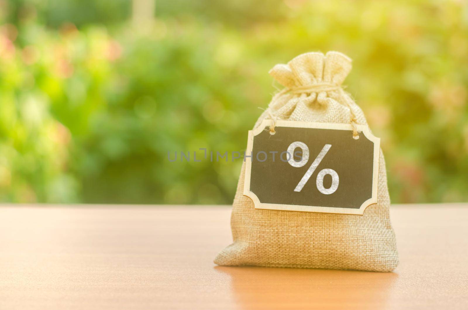 Bag with a sign and a percent symbol on the background of nature. Concept of deoposit or credit. Taxes Interest rate. The program of business support by soft loans. Banks and financial activities. by iLixe48