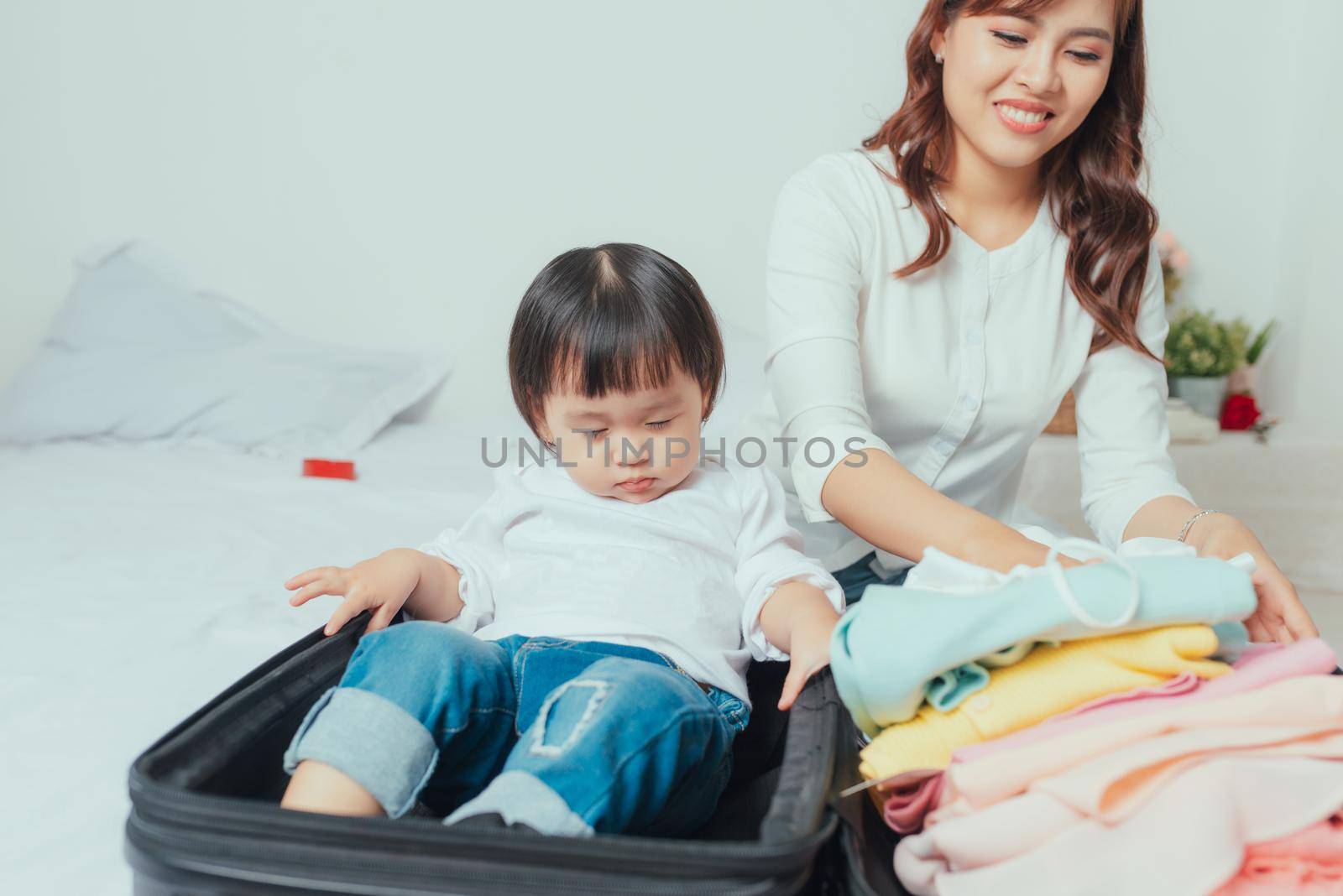 mother prepares clothes to put in her suitcase and her daughter plays with her suitcase by makidotvn