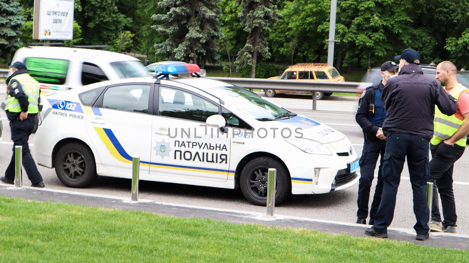 Ukraine, Kiev - June 2, 2020. Police patrol cars provide safety on the roads of Kiev in Ukraine. A male policeman stands near his car on the roadway.