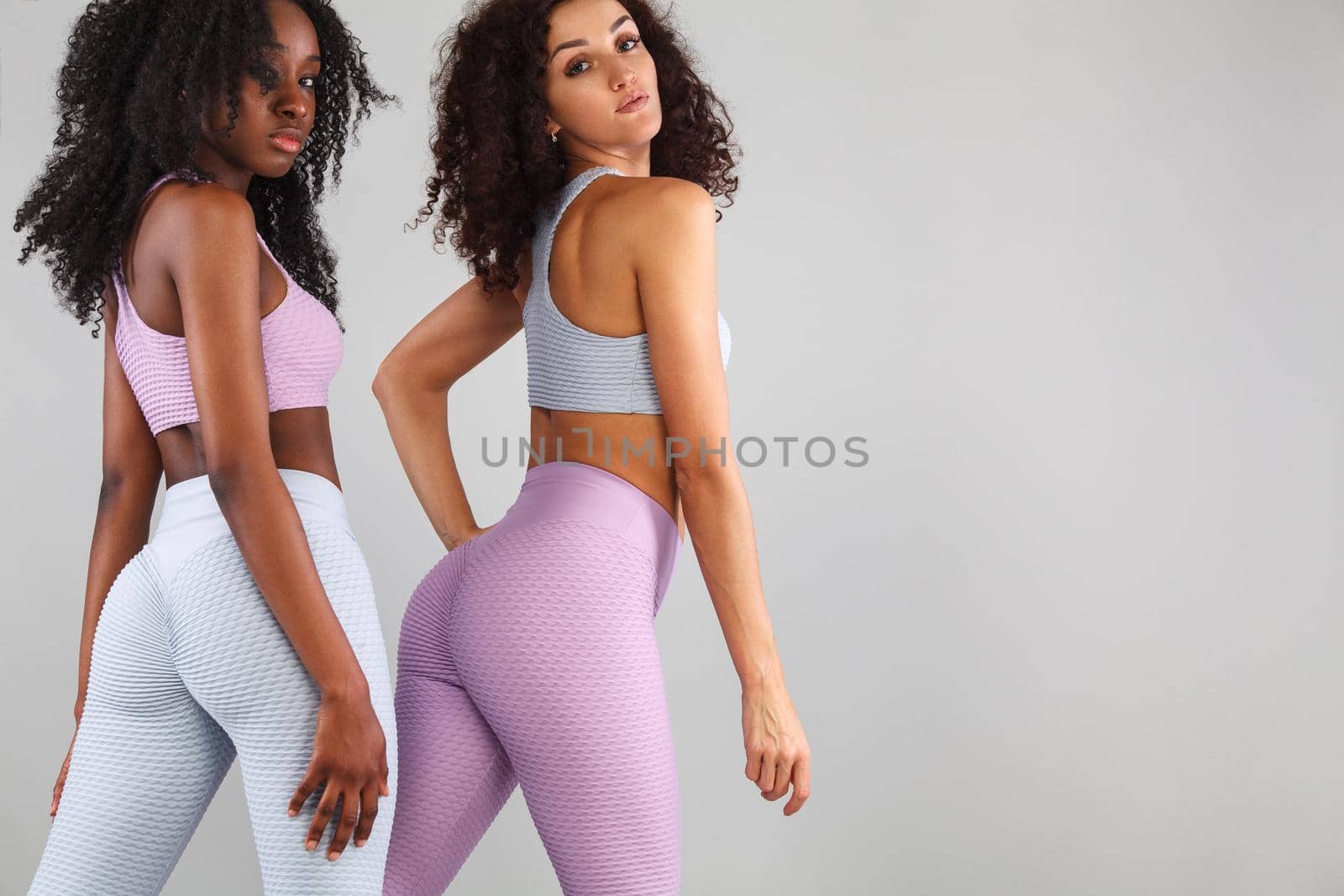Two fitness women in sportswear isolated over gray background. Sport and fashion concept with copy space. by MikeOrlov