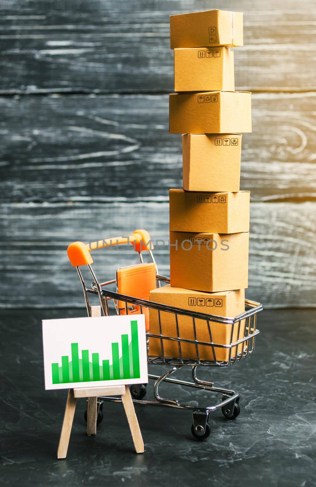 Shopping cart filled with boxes and a stand sign with a green positive trend chart up arrow. shopping online. development of Internet network trade. E-commerce. sales of goods and services