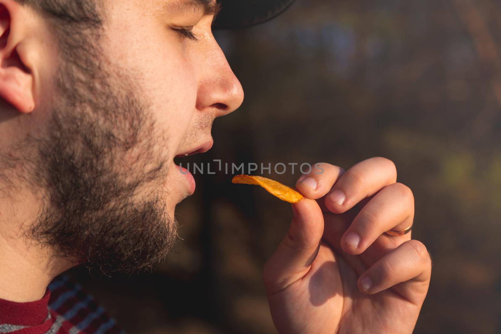 Bearder Man in forest eating chips. In park image outdoors with blurred background by lunarts
