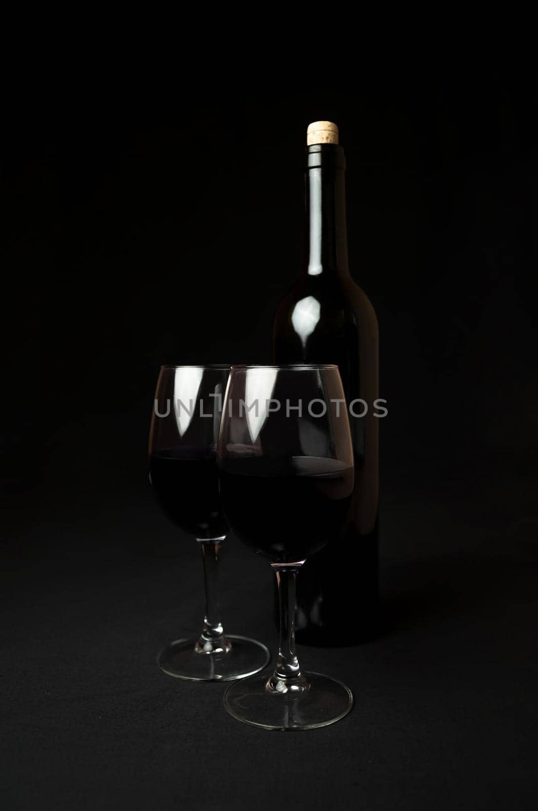 Red Wine. Bottle and Two Glasses of Red Wine on Black Background