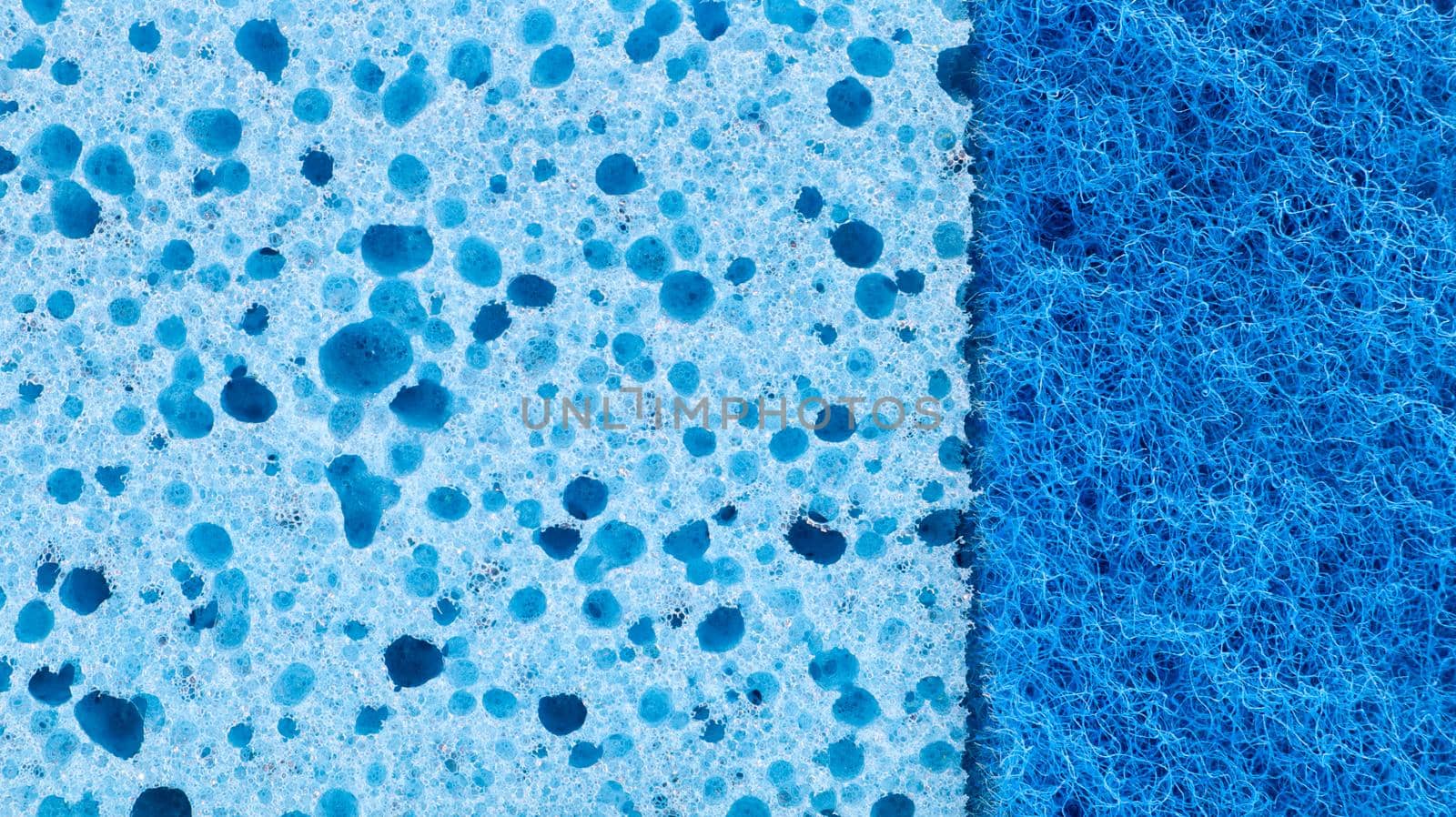 Background in the form of a porous structure in blue. Macro sponge. Close up blue sponge surface for textured background. copy space