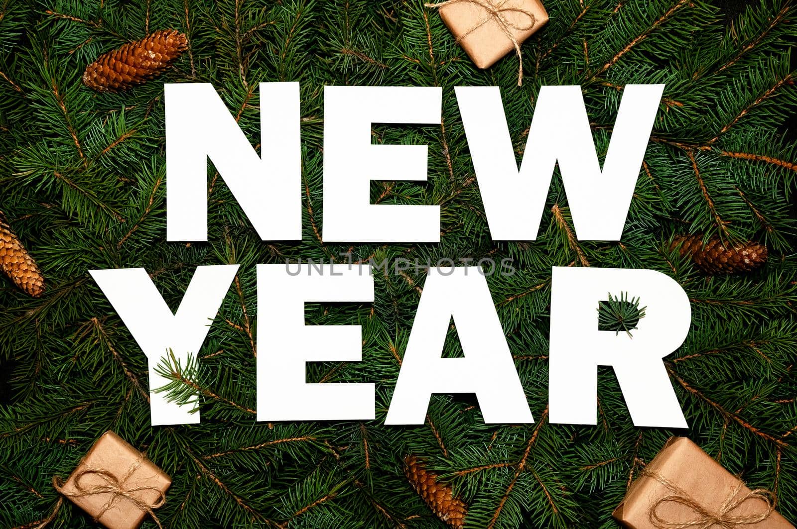 Words New Year on Green Fir Branches with Small Gift Boxs. Creative Nature Concept. Minimal Holiday Composition. Flat Lay.
