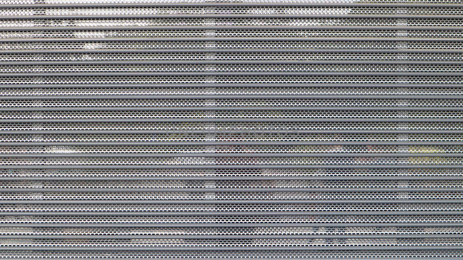 Close-up of a gray metal mesh as a security measure in front of a closed shopping center. Closed gates at the entrance to the store that impede the entry or destruction of places for criminals. by Roshchyn