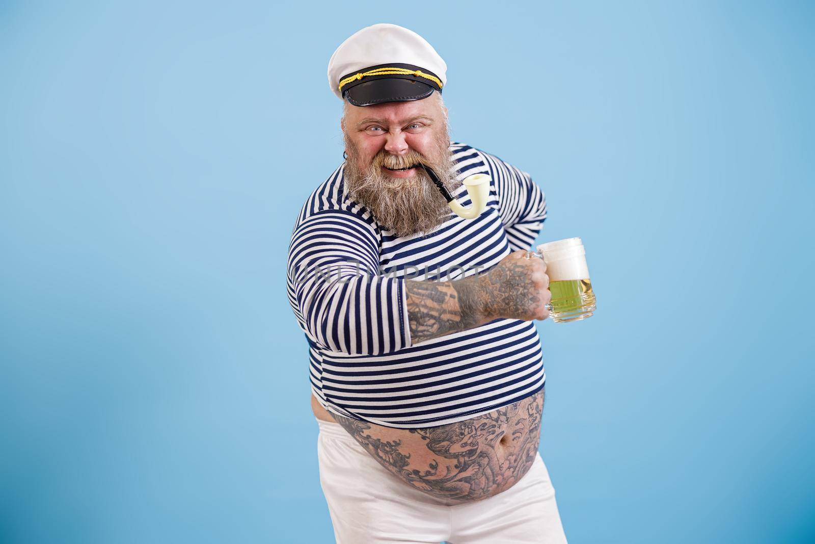 Happy plus size man in sailor suit holds delicious beer on light blue background by Yaroslav_astakhov