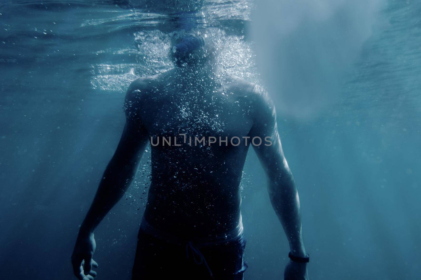 Freediver young man swimming to the surface of sea to breathe.