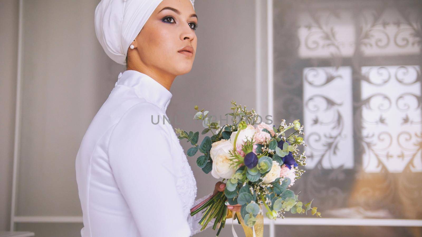 Young muslim bride with professional make up in wedding headdress with flowers bouquet, close up